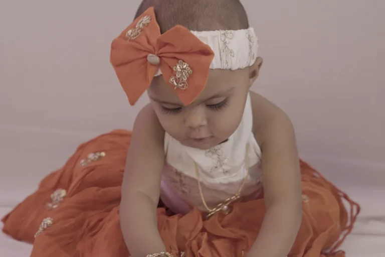 Baby in a bow headband sitting on a rug