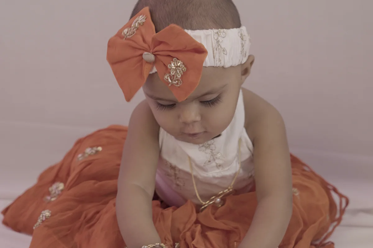 Little girl in a bow headband wearing ANIKI kids jewellery