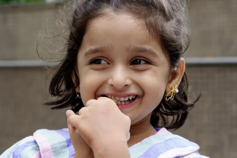 Young girl smiling while wearing ANIKI earrings